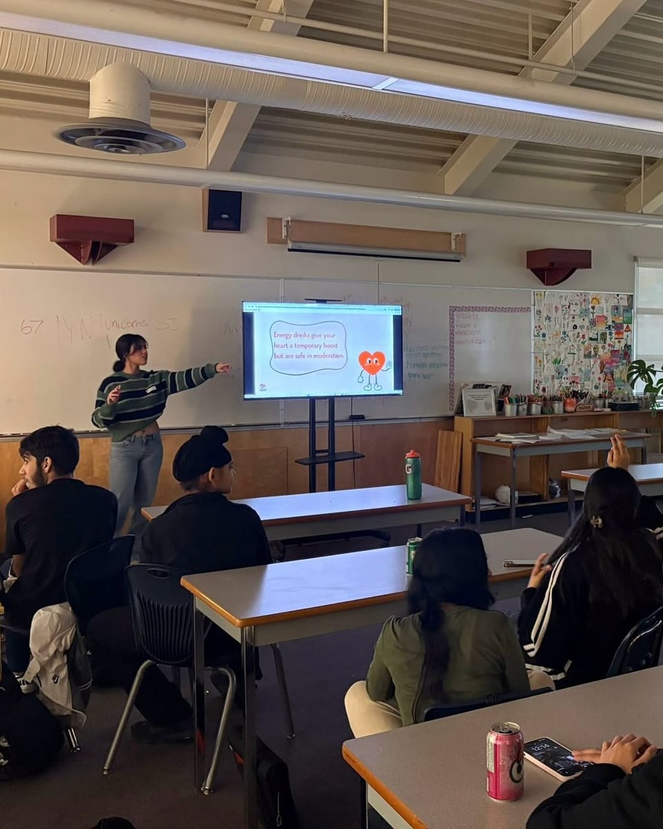 Students watch a slide with a red heart on the classroom screen.